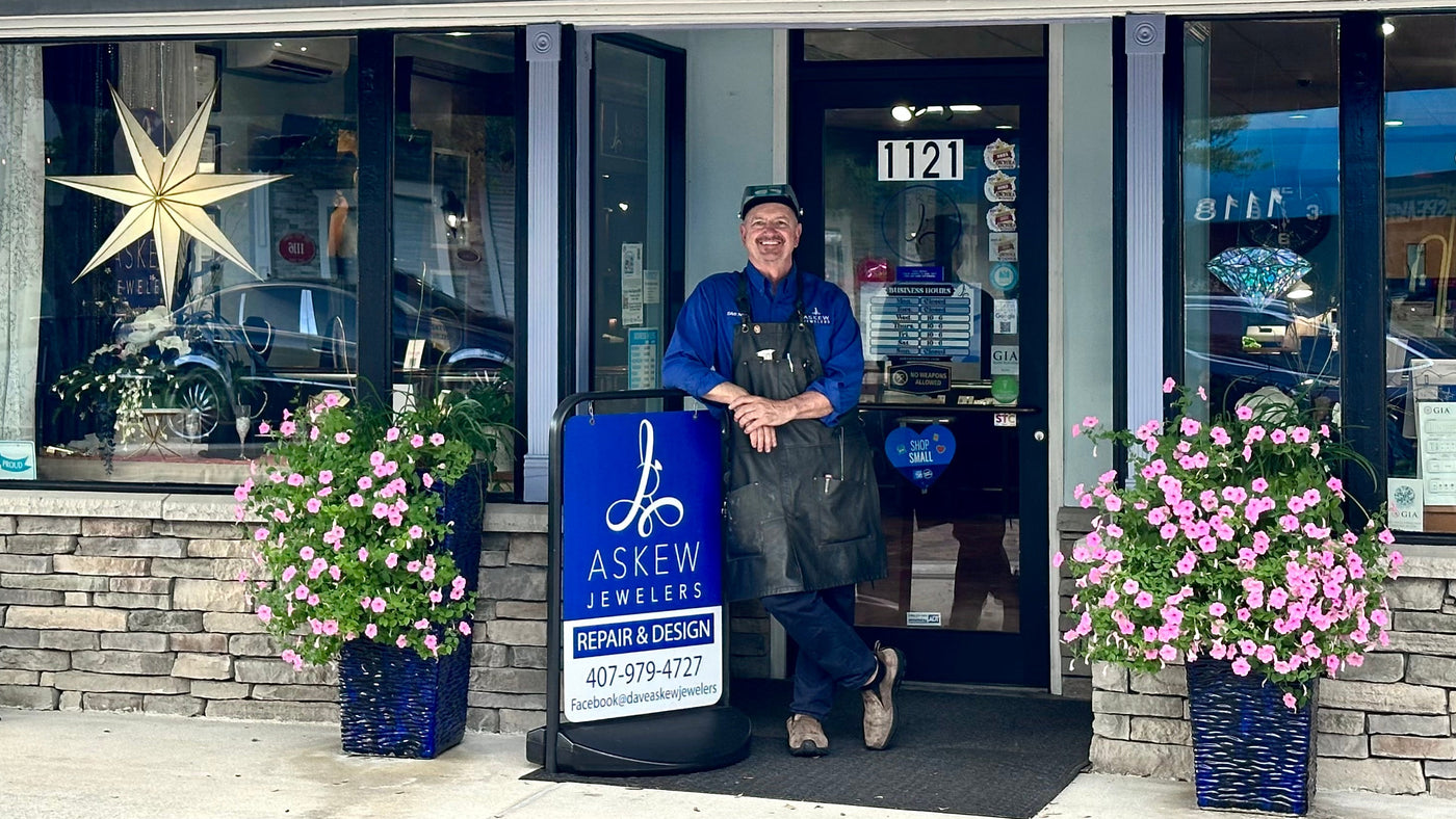 Dave Askew standing outside Askew Jewelers with pink flowers on either side.